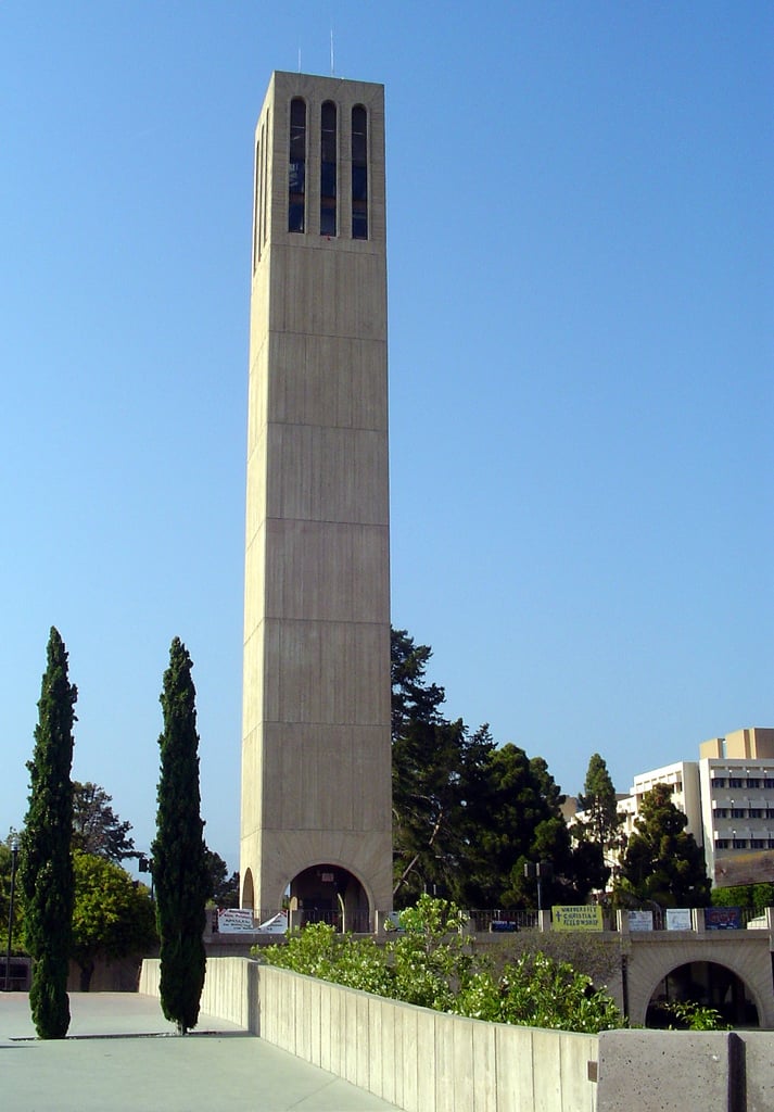 The tall, plain concrete Storke Tower on the UC Santa Barbara campus against a blue sky